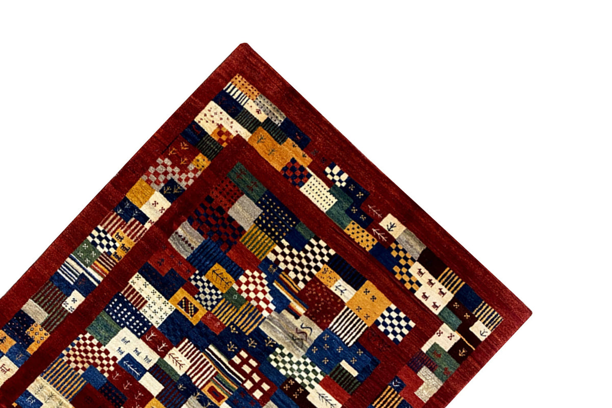 Corner of the rug with patchwork sections in blue, red, beige, and green