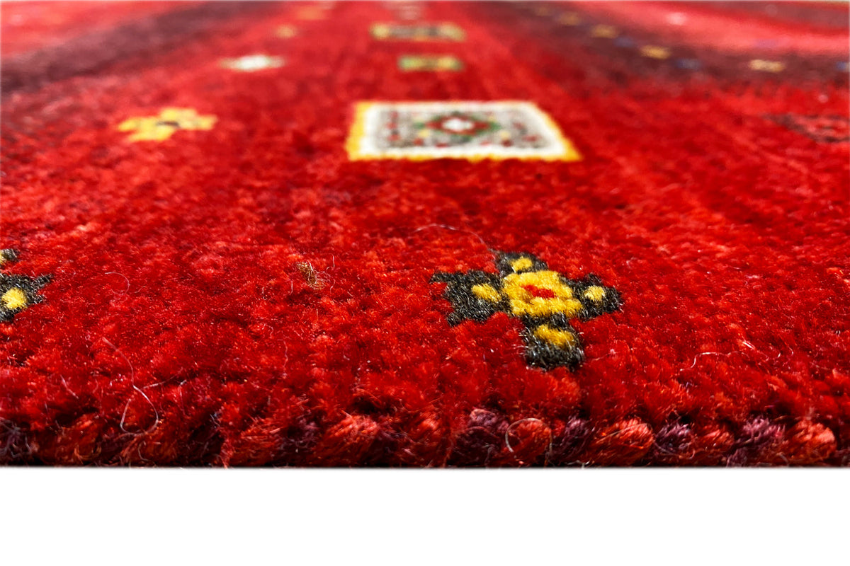 Close-up of a red carpet surface with multicolored embroidery/appliqué in the center