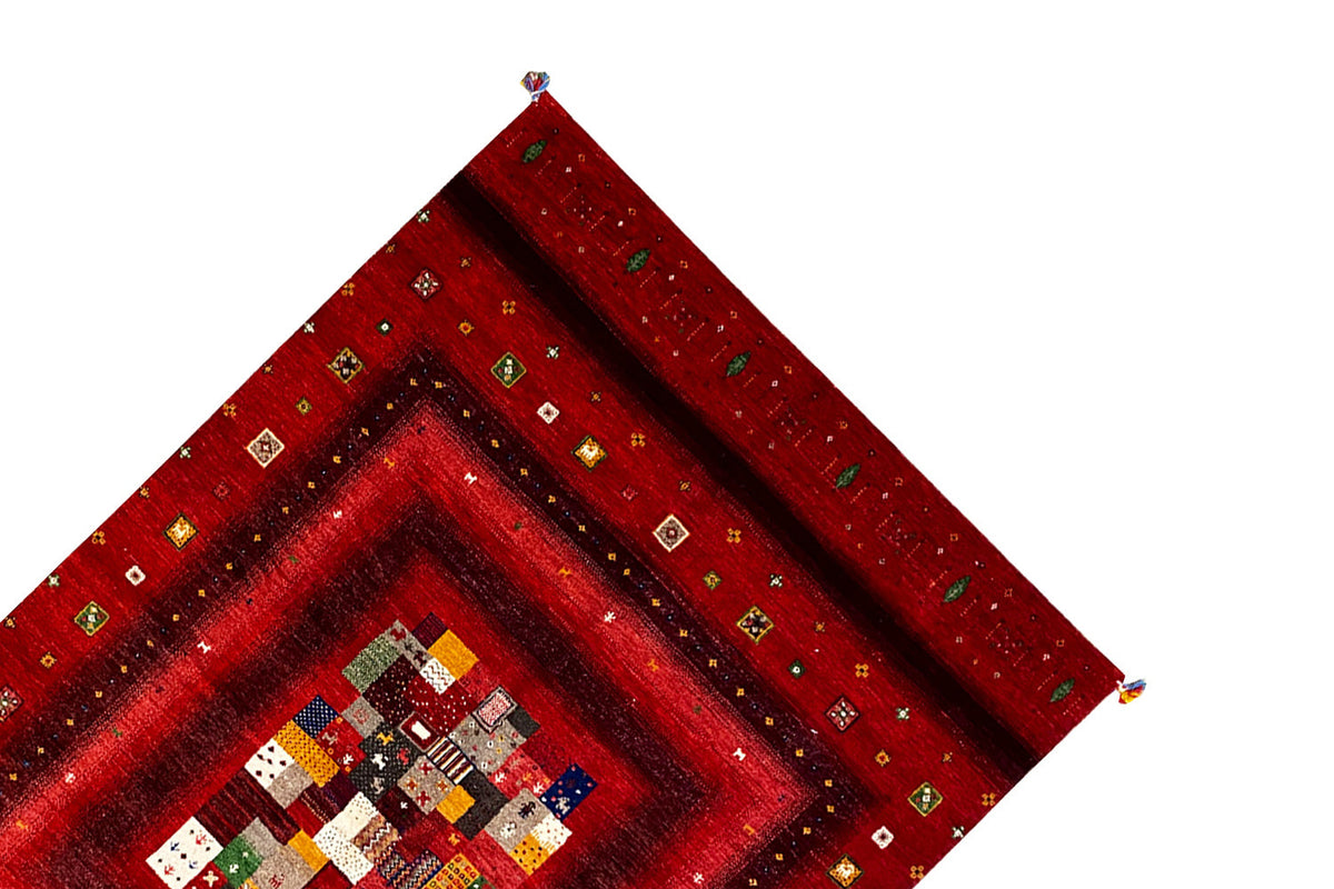Folded red Gabbeh rug with a central patchwork medallion and colorful accents