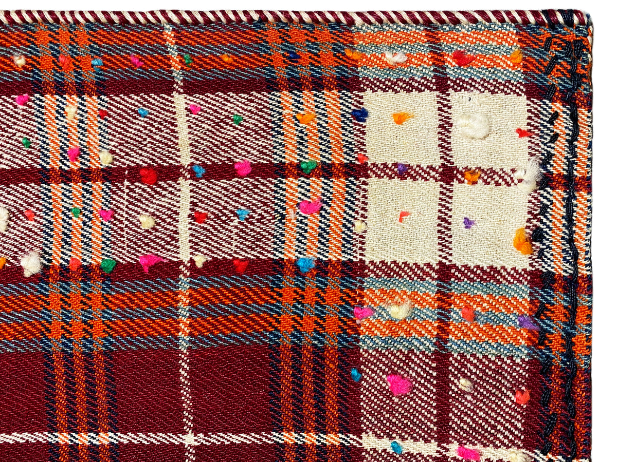 Close-up: carpet fabric with a checkered pattern, colorful dots, and a multicolored border