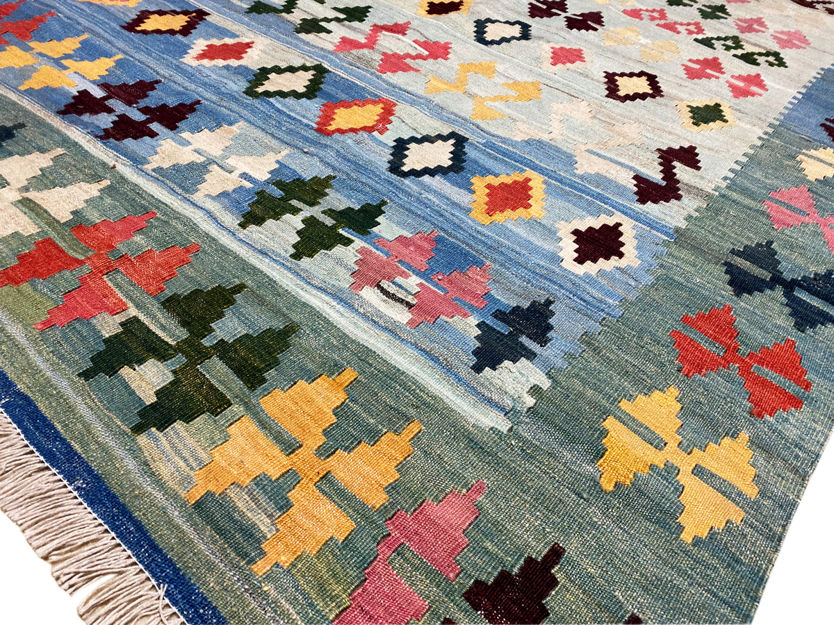 Detailed view: blue kilim with colorful cross, diamond, and zigzag motifs, woven surface