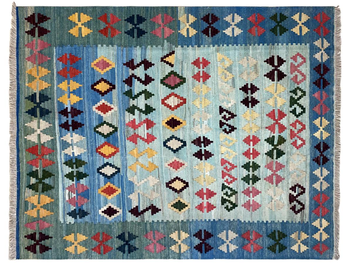 Close-up: blue kilim with a dense diamond, cross, and zigzag pattern, colorful woven texture