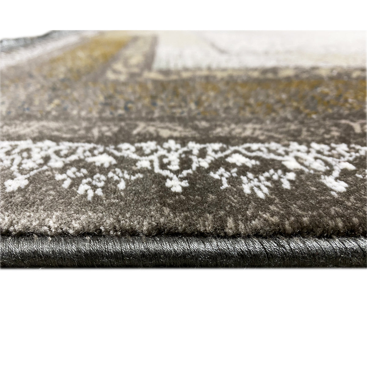 Carpet edge in detail with short fringes and dense pile, patterned in light and dark brown/gold