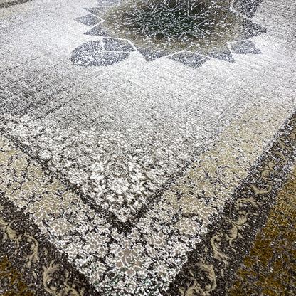 Carpet detail with a silvery fiber look, ornamental pattern, and dark border