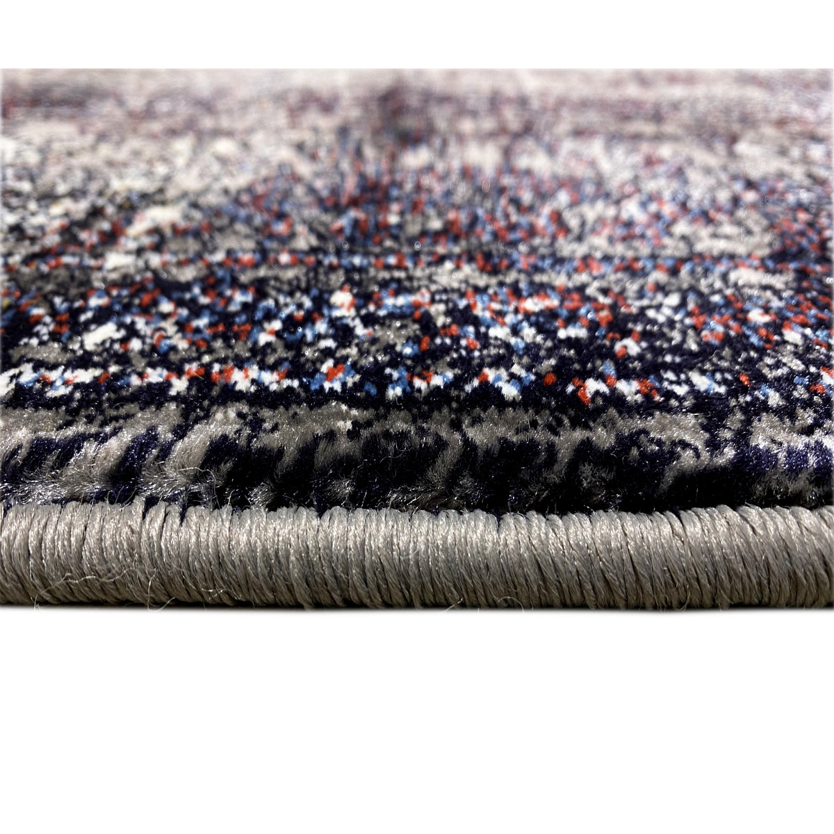 Close-up of the fringed edge and pile of the vintage rug in dark gray with colorful accents