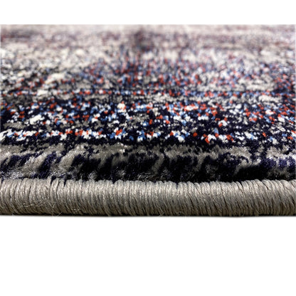 Close-up of the fringed edge and pile of the vintage rug in dark gray with colorful accents