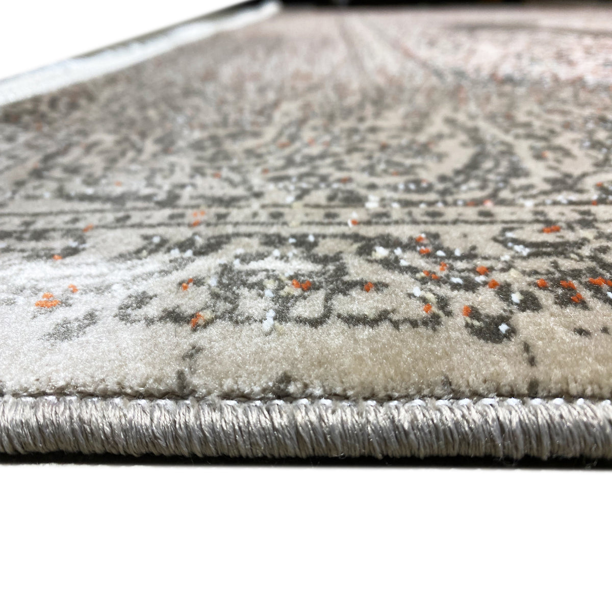 Rug edge with fringes and a silver-gray patterned surface, tightly woven texture