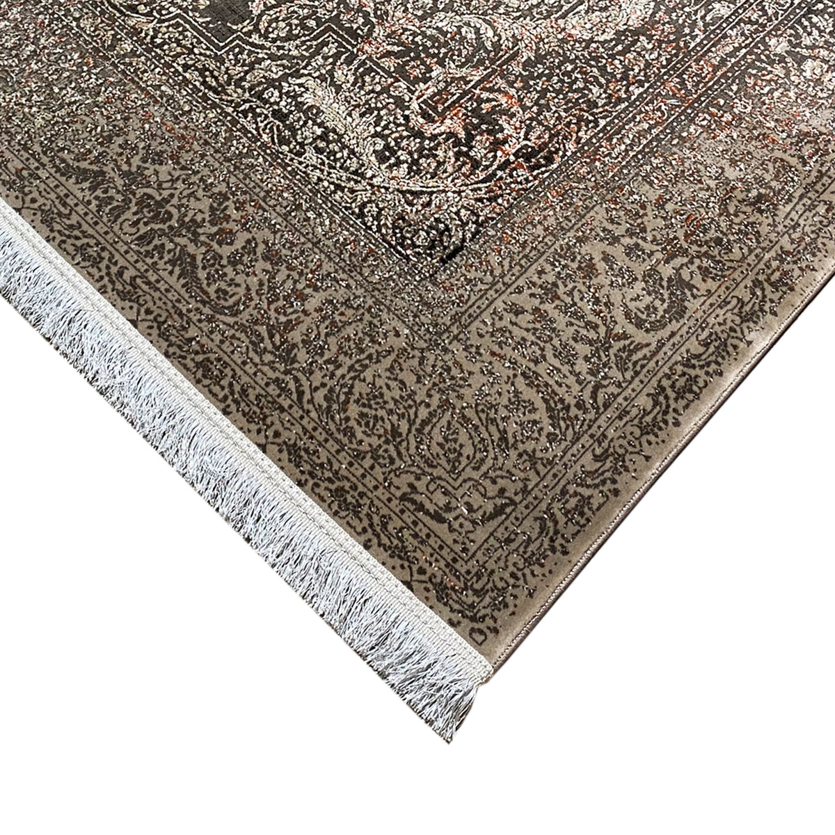 Corner of the rug with a dark linear pattern, silver-gray background, and fringe