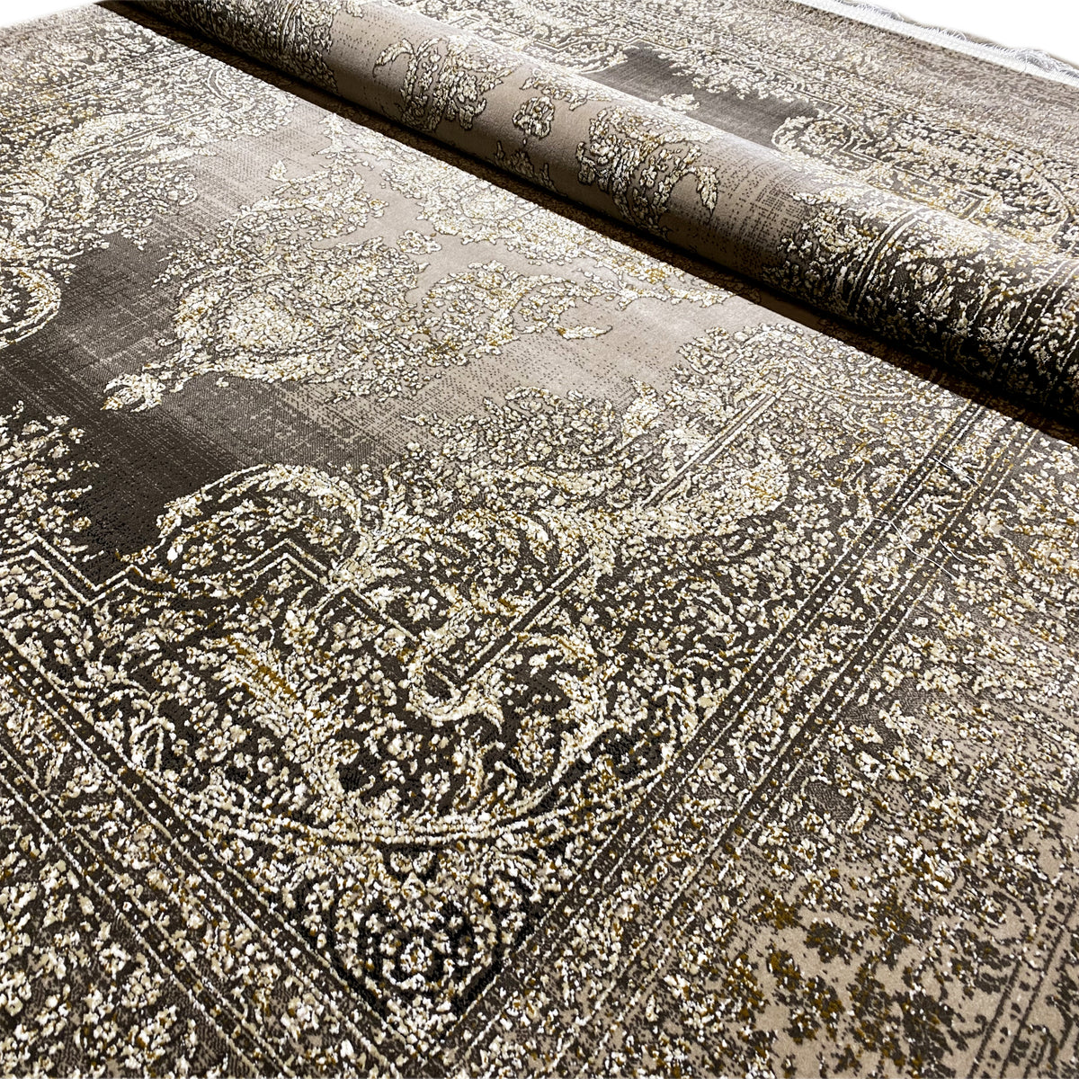 Rug detail with a gold-beige Baroque pattern on a dark gray background