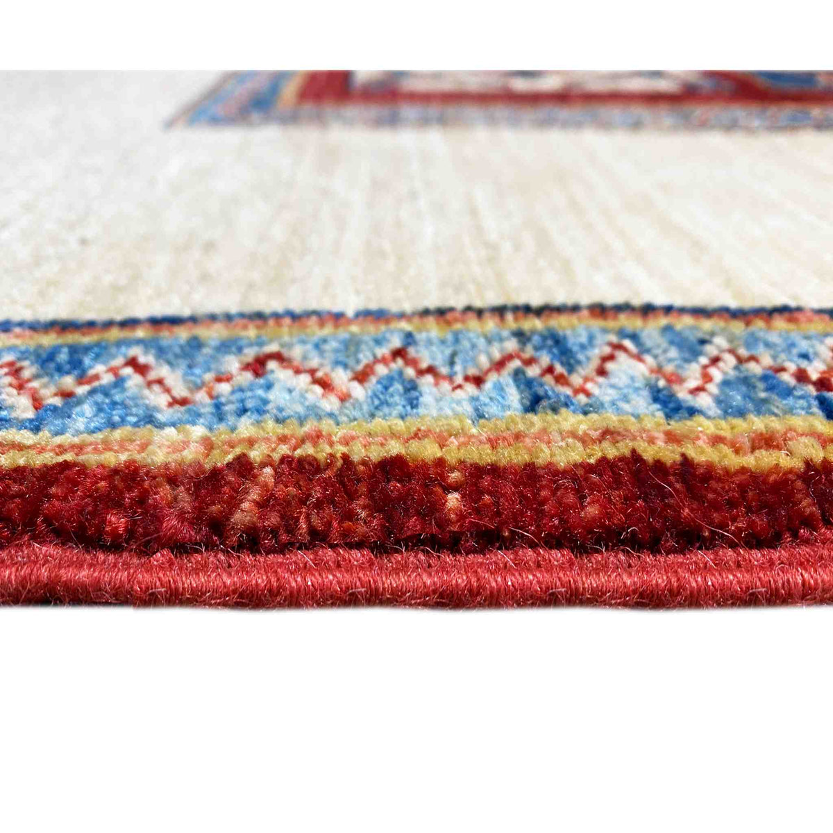 Close-up of the carpet edge: dense pile, cream-colored base with red sectional stripes