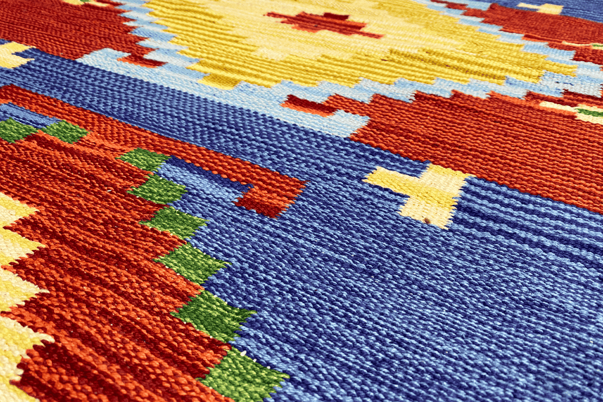 Detail of the kilim dhurrie rug: colorful threads, geometric motifs in blue, red, and yellow