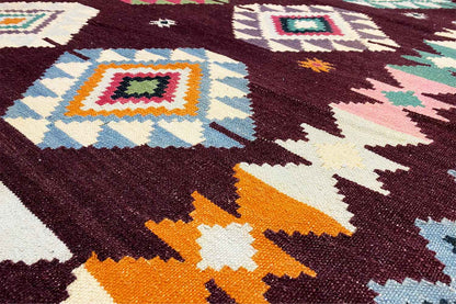 Close-up of a kilim rug: diamond-shaped patterns in dark red, orange, turquoise, and cream