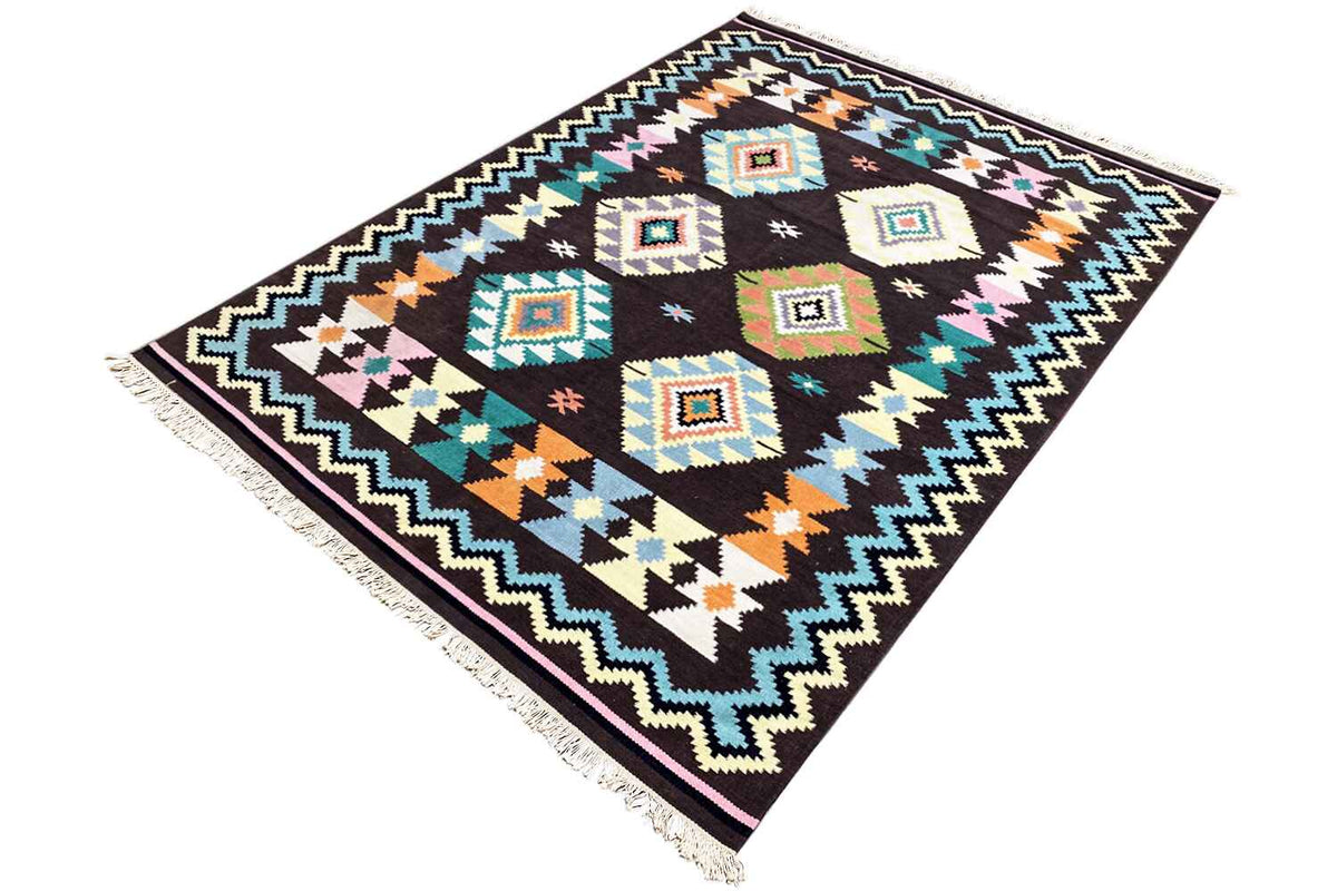 Corner view of a kilim rug: diamond pattern, colorful zigzag border, and fringes