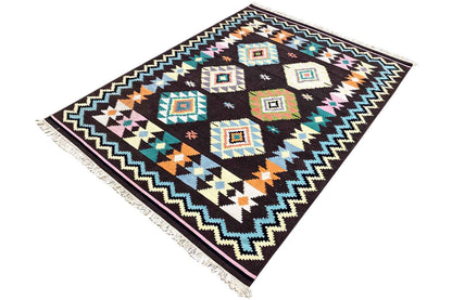 Corner view of a kilim rug: diamond pattern, colorful zigzag border, and fringes