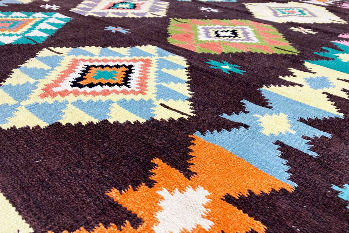 Close-up of a kilim rug: colorful squares and triangles on a dark textile surface