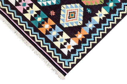 Side view of a kilim rug with fringes and a zigzag border, black, blue, orange