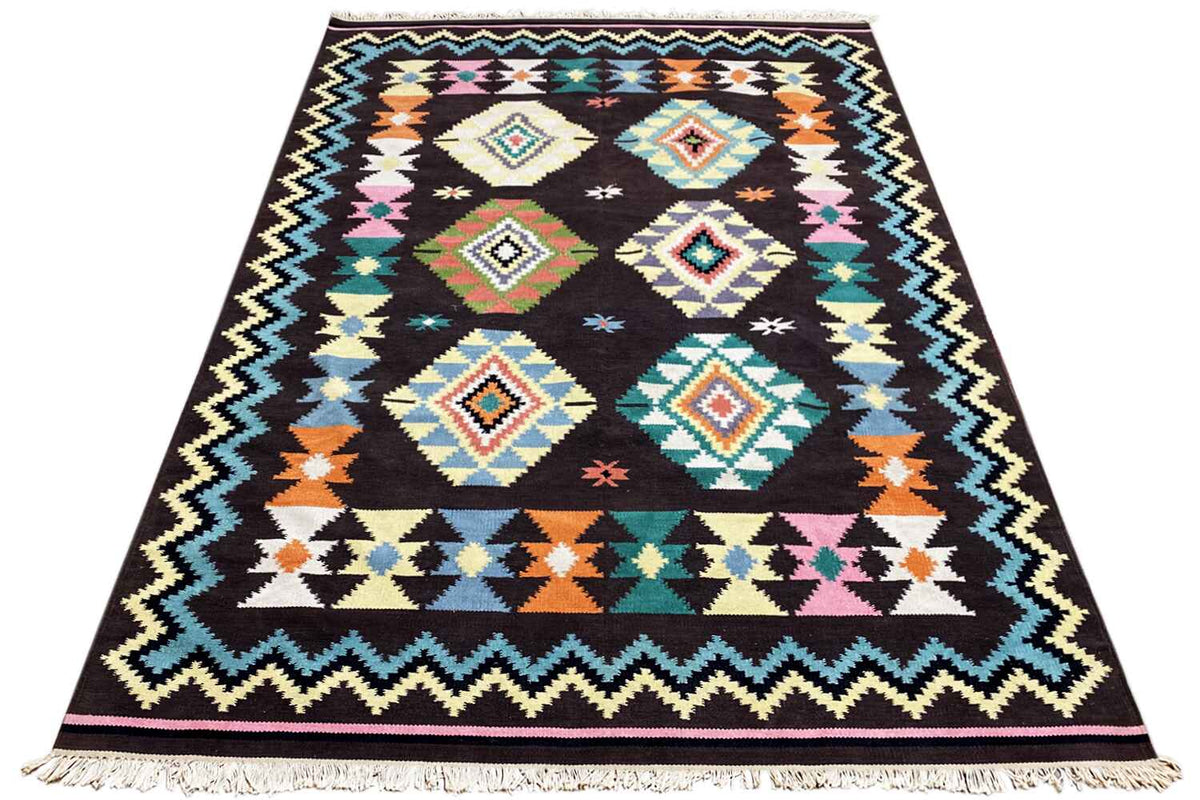 Kilim rug with a geometric tribal pattern on a dark background, colorful accents, and fringes