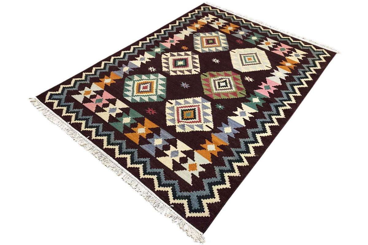 Wool kilim rug, shown at an angle, with diamond and zigzag patterns and fringes