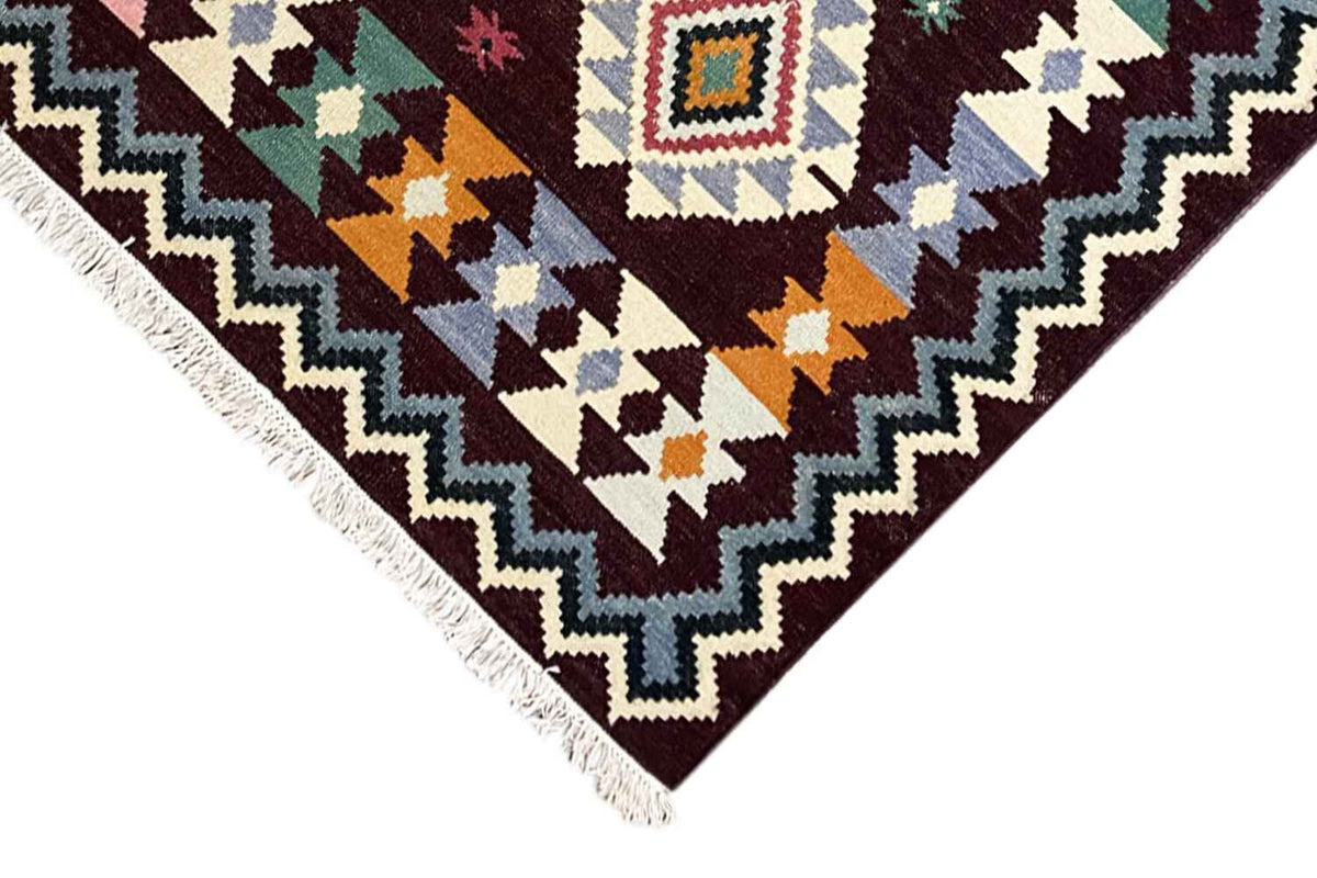 Wool kilim rug corner with zigzag border, colorful diamonds, and white fringes