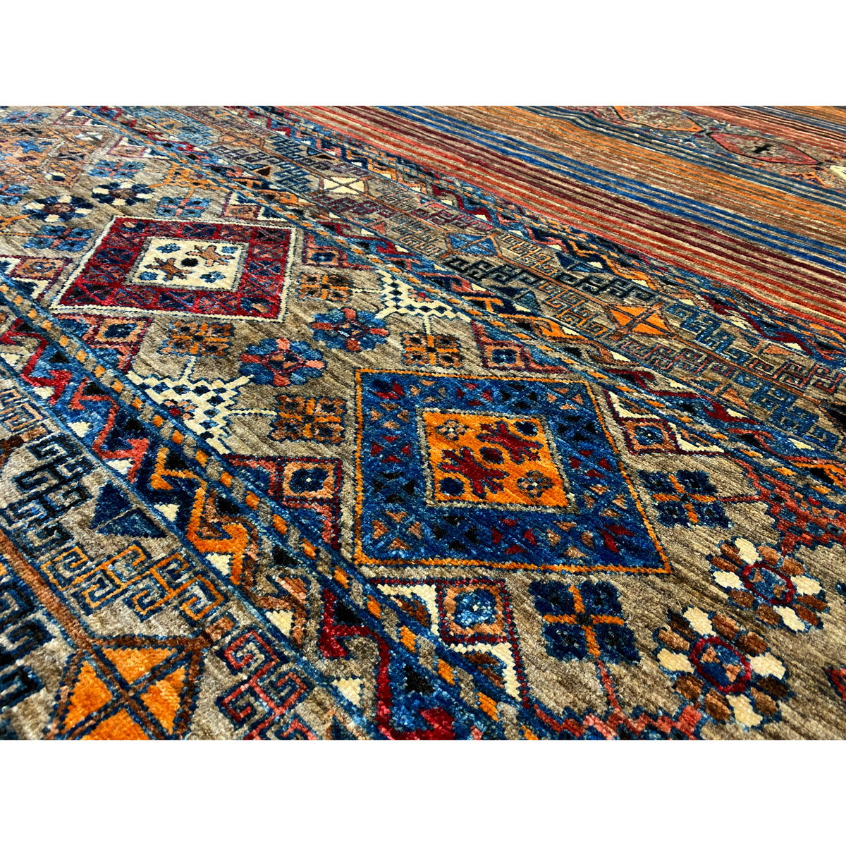 Close-up of the colorful carpet pattern with squares, lines, and ornaments in blue, red, and beige.