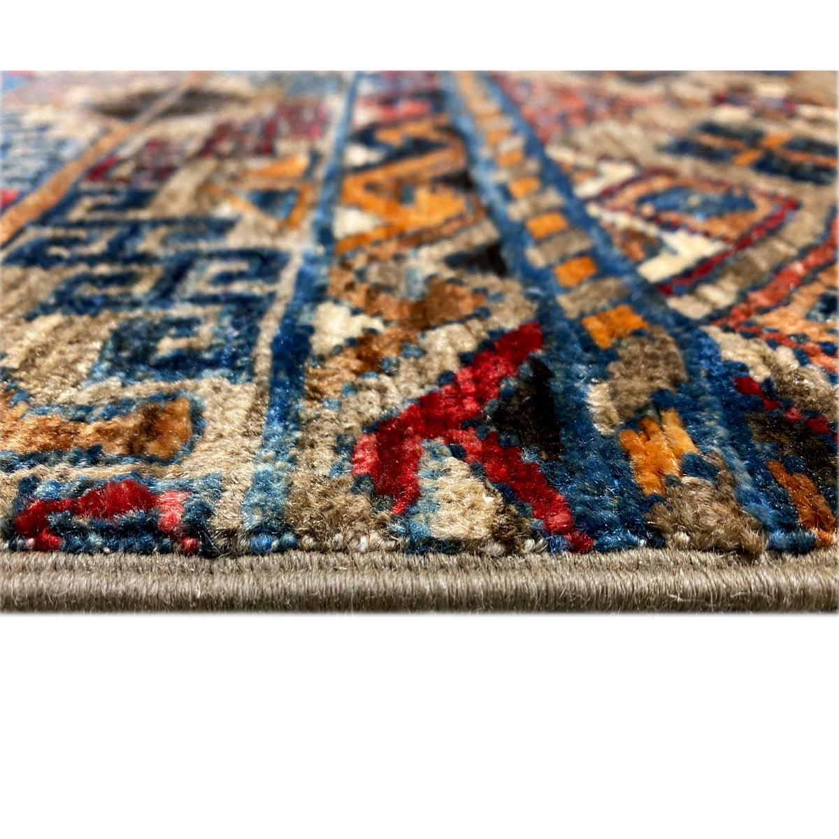 Close-up of a carpet surface with colorful ornaments and a dense pile, with a visible hem.
