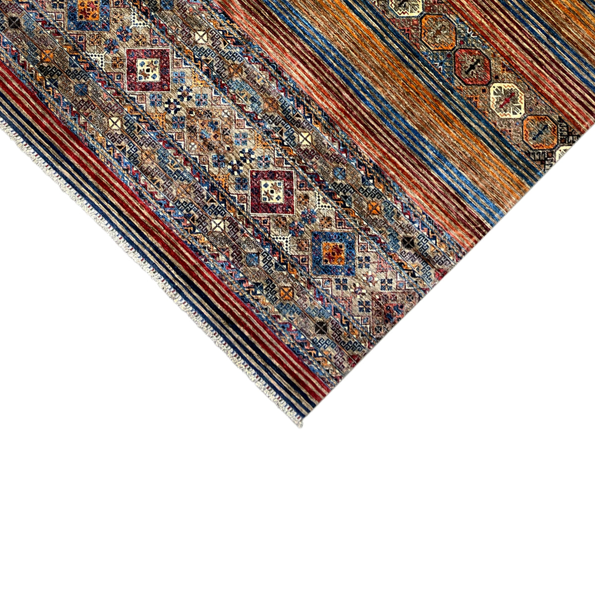 Corner of a colorful rug with a fine geometric pattern and fringed edges.