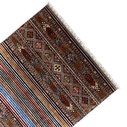Colorful Khorjin rug at an angle, border with diamond panels and light-colored fringe