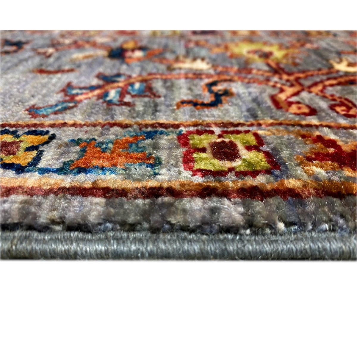 Close-up of the carpet edge: gray Oriental rug with fringe and woven texture