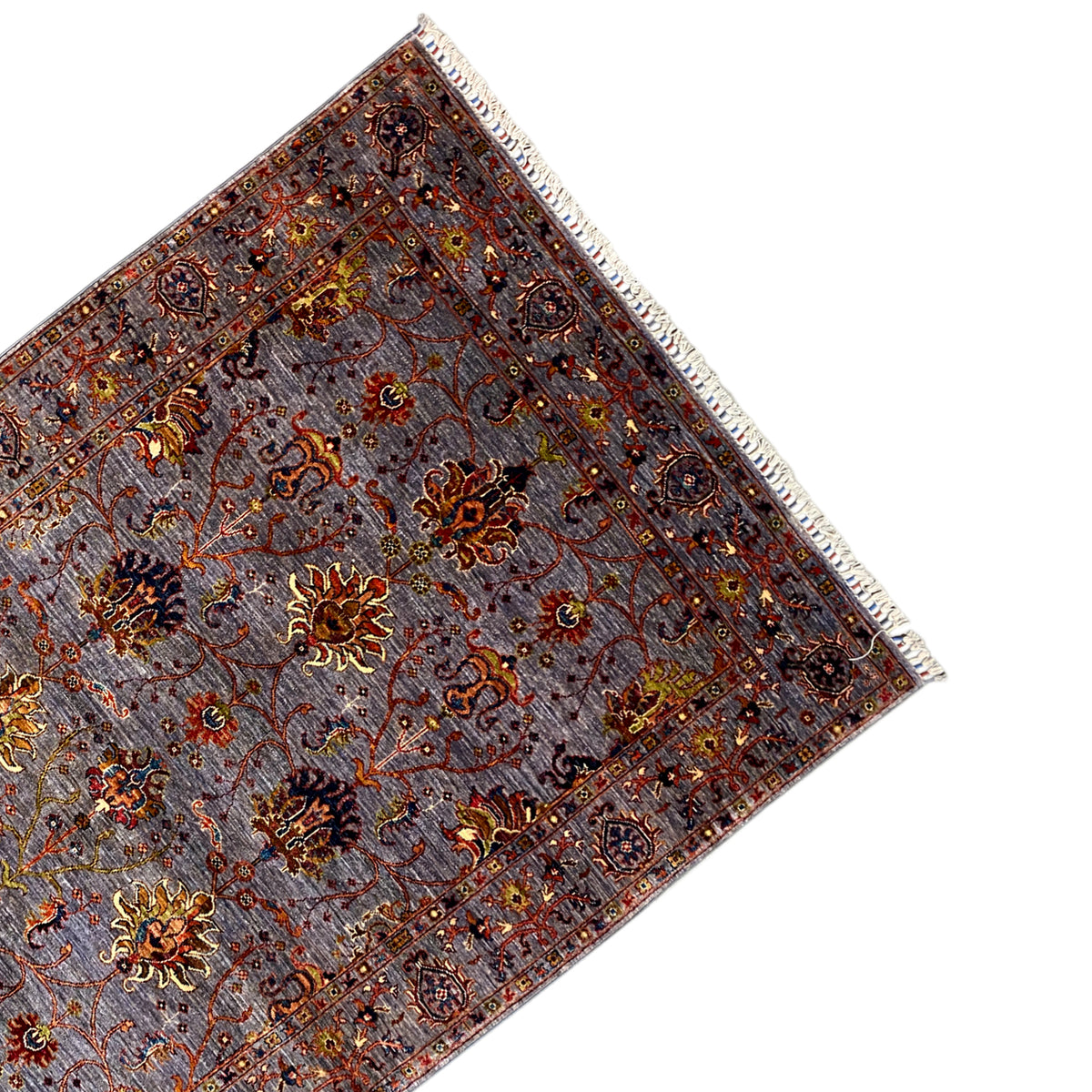 Corner of the gray Oriental rug with a border, floral ornaments, and fringes