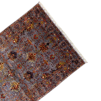 Corner of the gray Oriental rug with a border, floral ornaments, and fringes