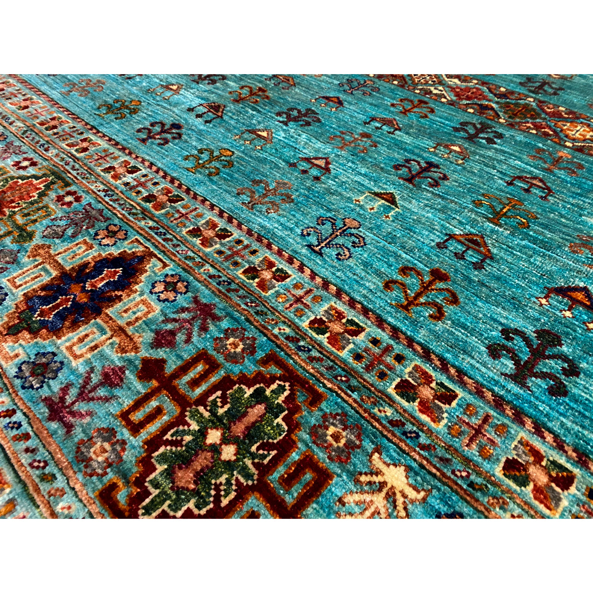Close-up: turquoise rug with colorful geometric ornaments and pile texture