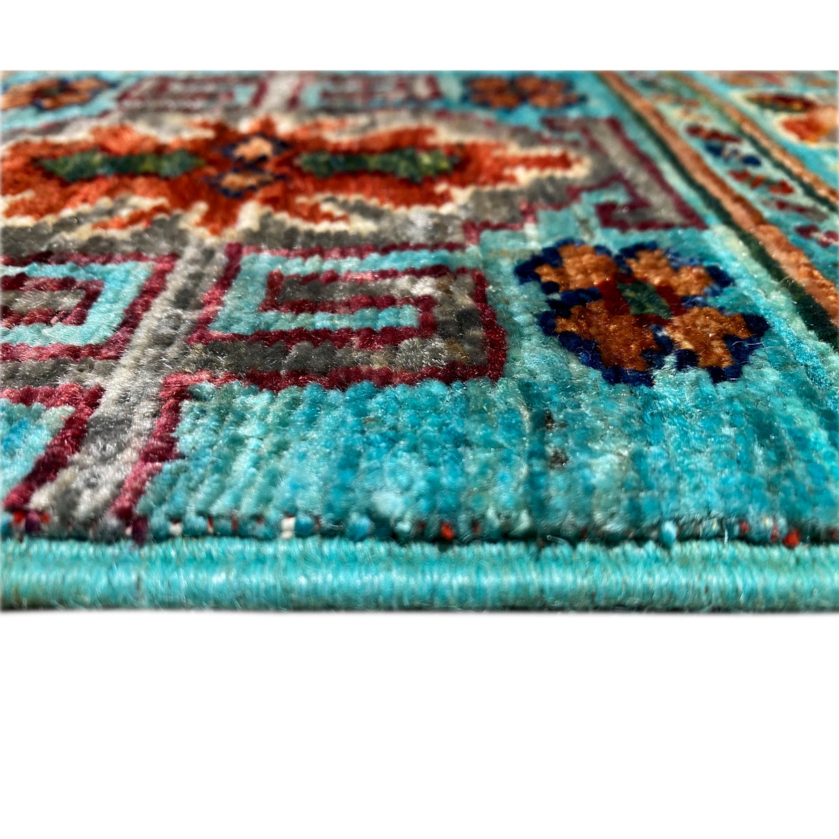 Close-up of a border: turquoise rug with multicolored patterns and fringes