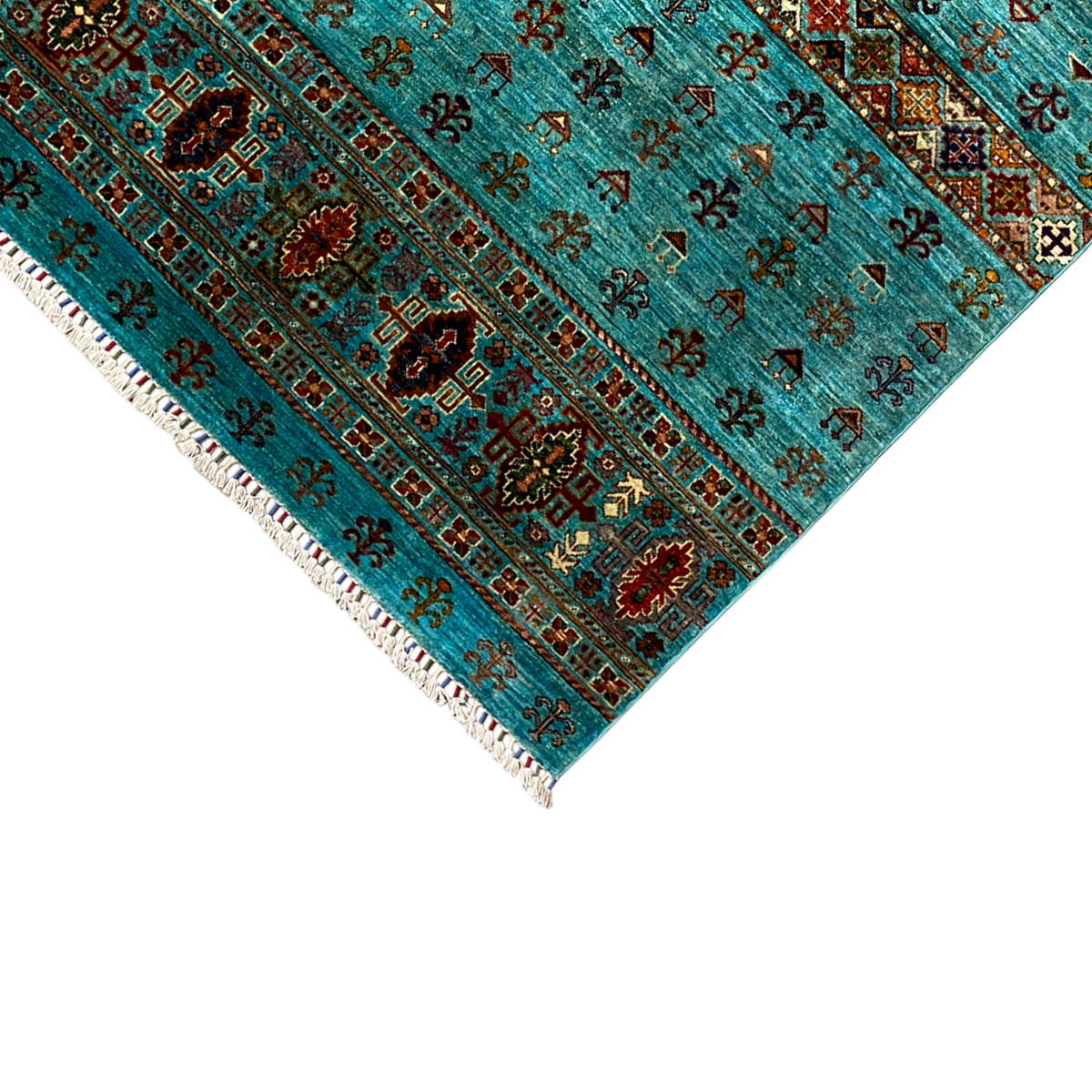 Corner of a turquoise rug with an ornamental border and white fringes