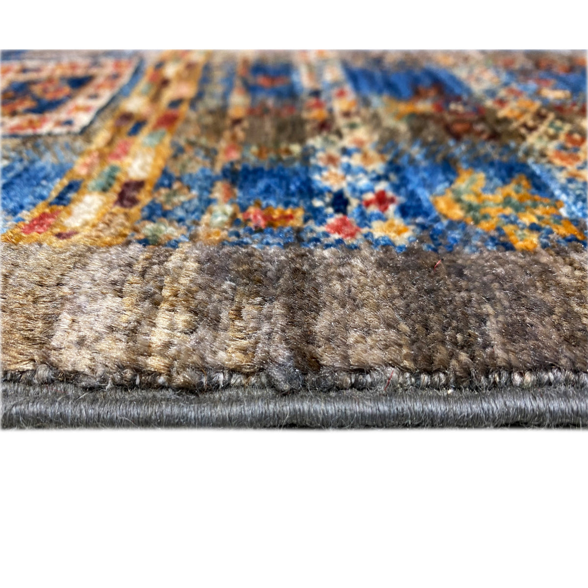 Rug border with dense gray-brown pile, colorful patterned area, and white fringe strip