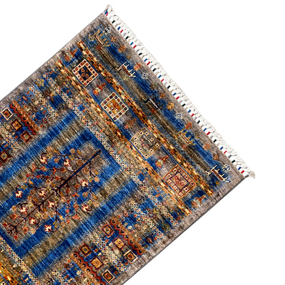 Corner view: blue-brown Khorjin rug with medallion design and white fringed edge