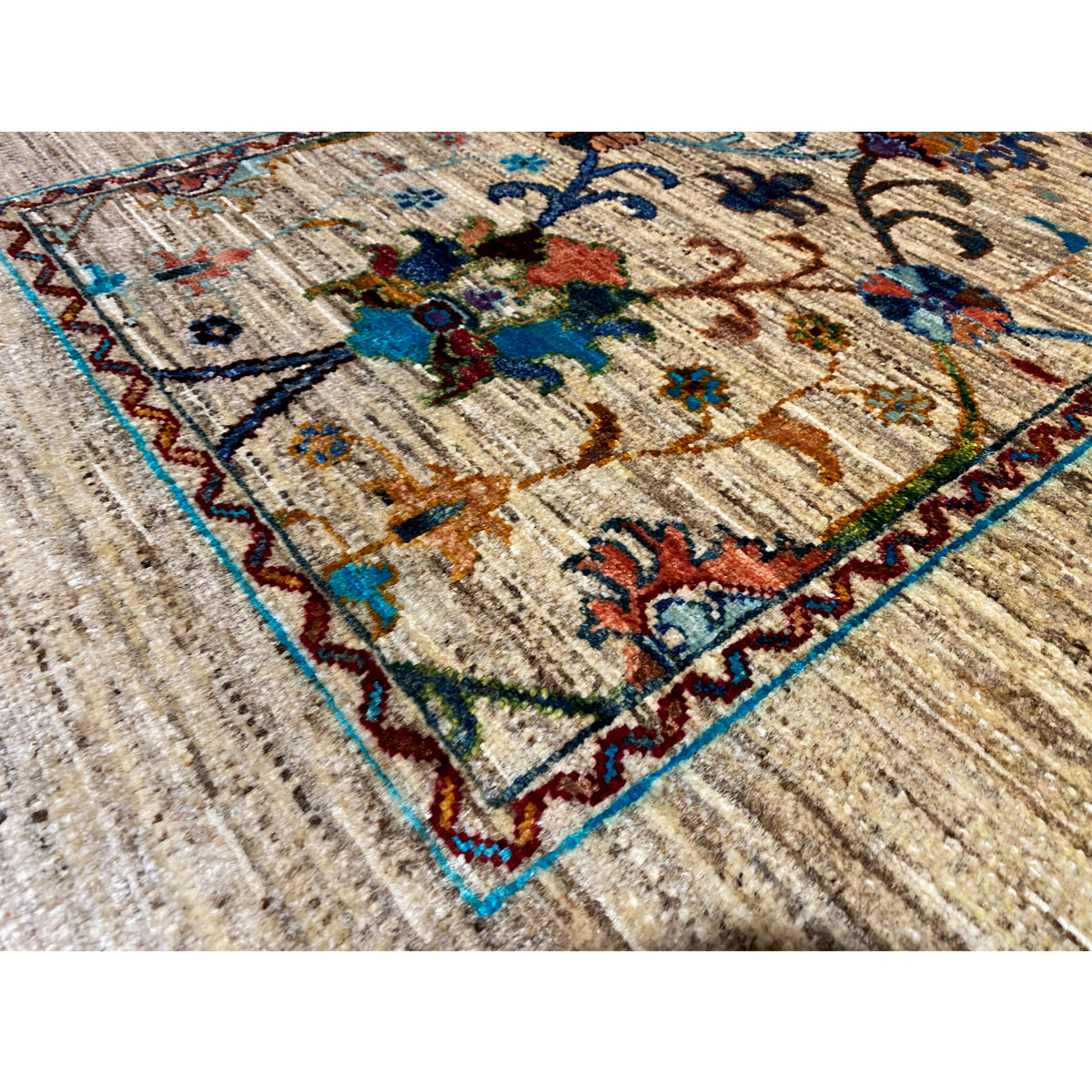 Close-up of Khorjin rug: beige pile with blue-red multicolored floral ornaments and a border edge