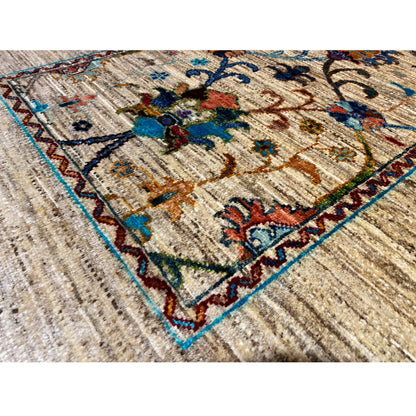 Close-up of Khorjin rug: beige pile with blue-red multicolored floral ornaments and a border edge
