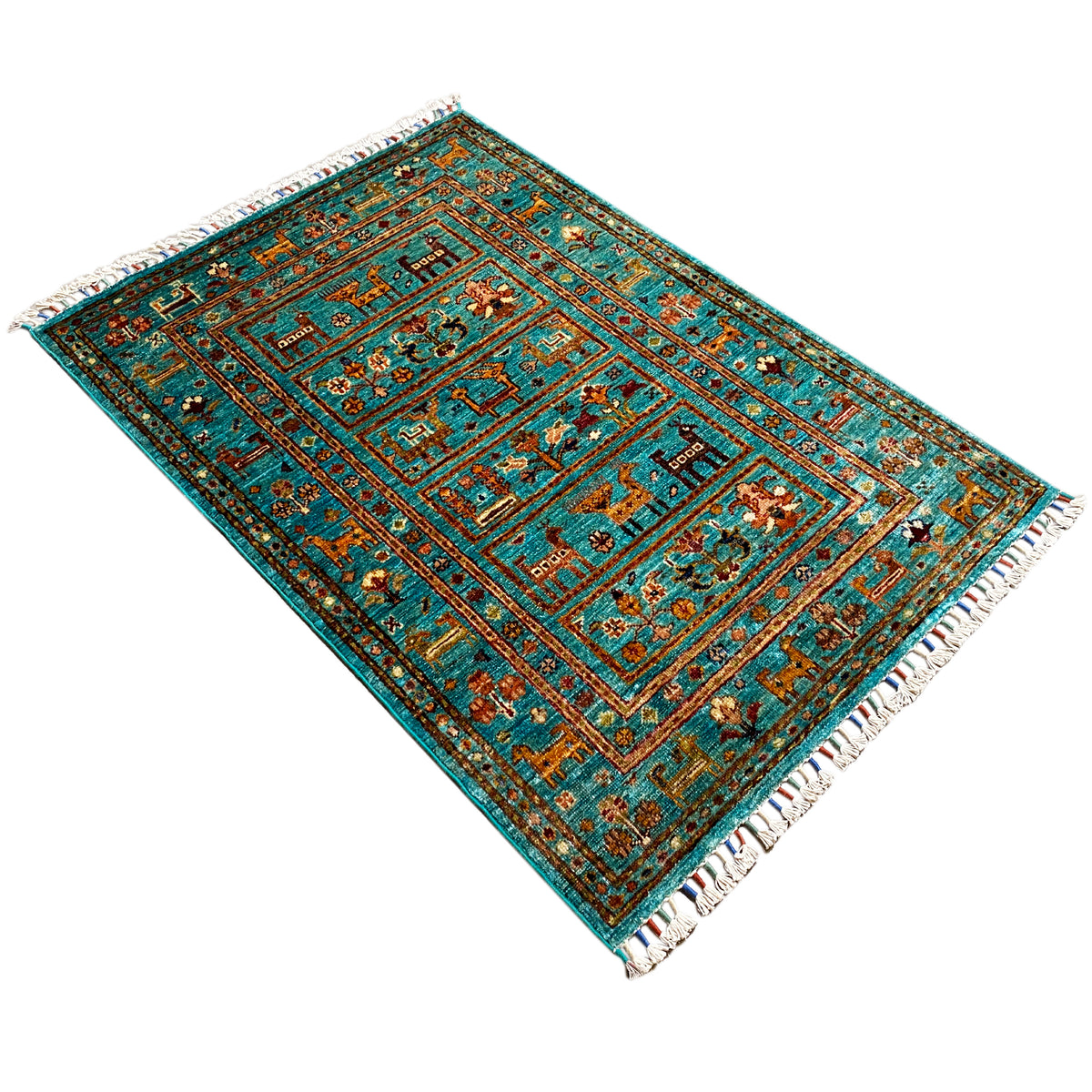 Turquoise Khorjin rug viewed diagonally, with a central medallion and fringes.