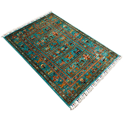 Turquoise Khorjin rug viewed diagonally, with a central medallion and fringes.