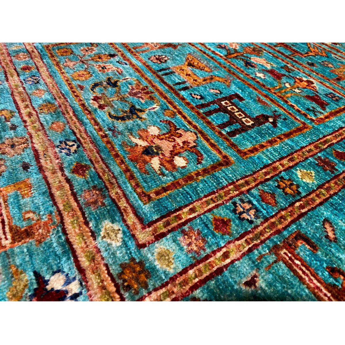 Close-up of a turquoise carpet surface with colorful ornaments, framed by borders.