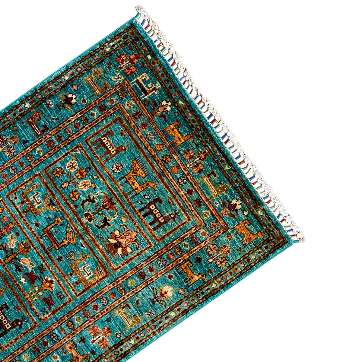 Corner of a turquoise Khorjin rug with ornaments and white fringe along the edge.