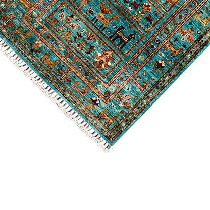 Close-up of the turquoise carpet corner with a border trim and white fringes, decorative field pattern.