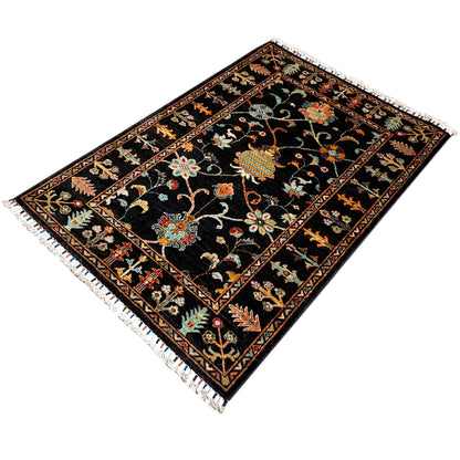 Khorjin rug viewed from above at an angle: dark field with floral patterns and a border, fringes