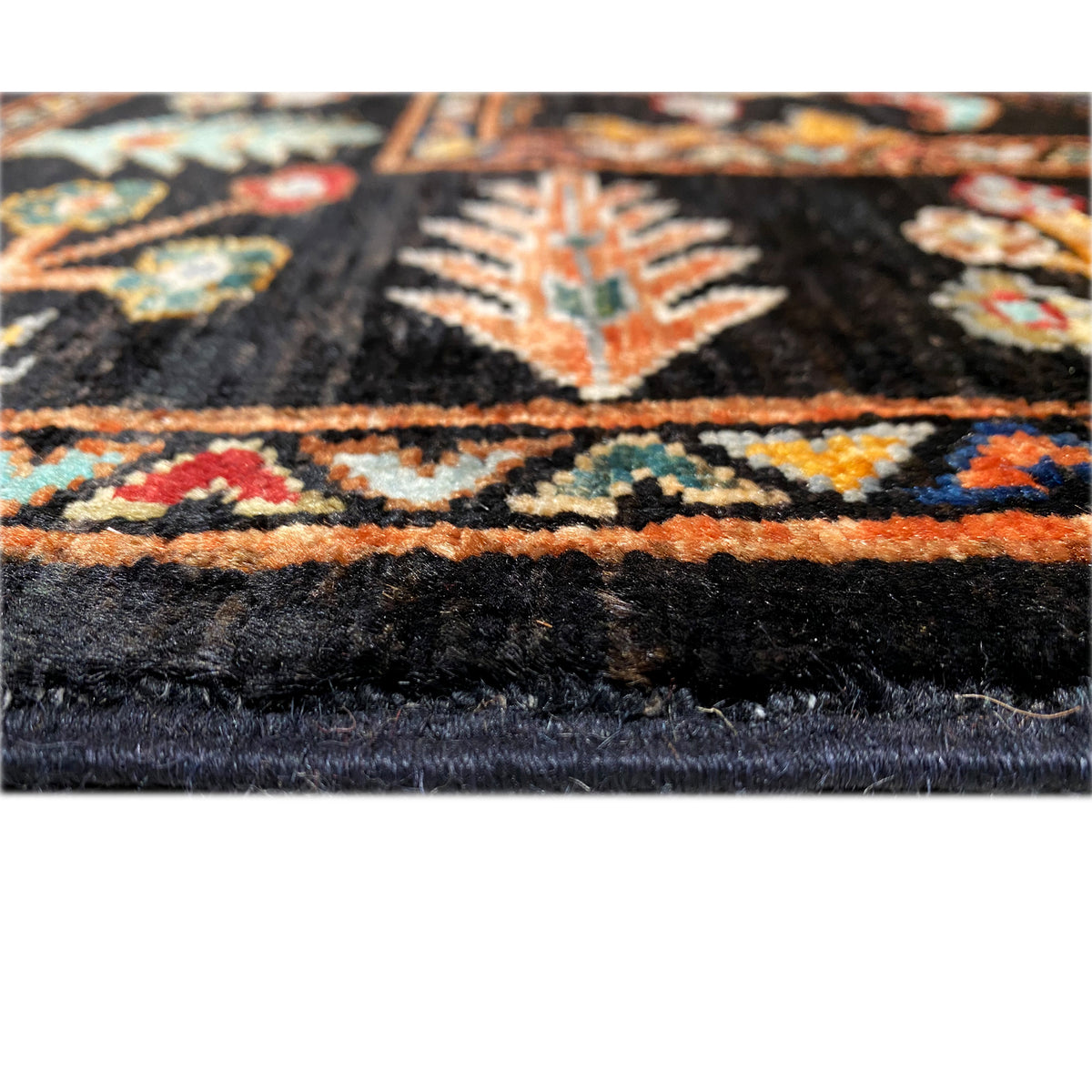Khorjin rug close-up of the edge: dark pile with a colored border and fringes