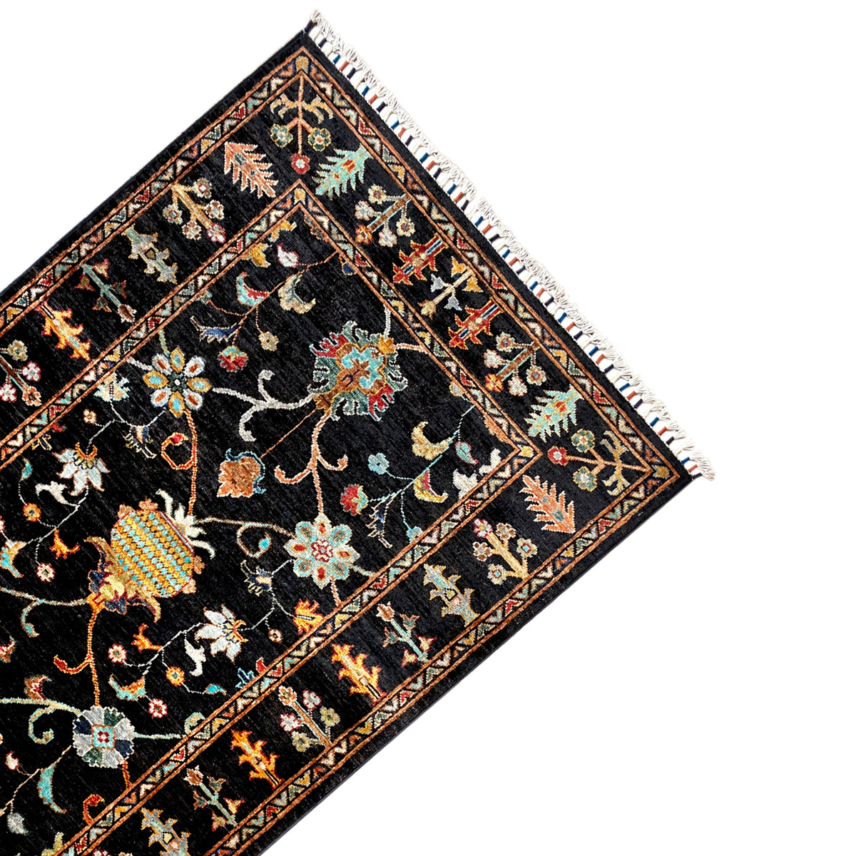 Khorjin rug at an angle: dark central motif with colorful flowers, vines, and a delicate border, fringes