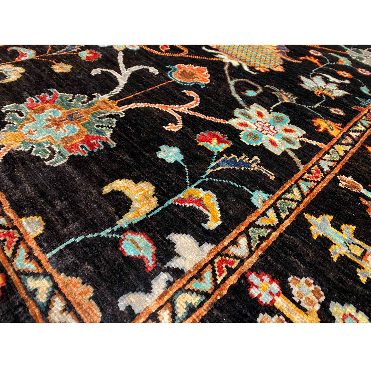 Detail view of the Khorjin rug, 143x96 cm: black pile with colorful hook and floral motifs