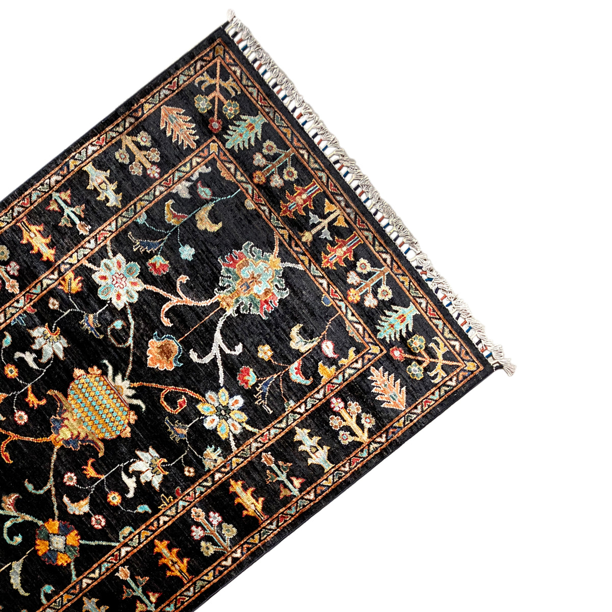 Khorjin rug 143x96 cm angled view: black background with colorful ornaments, fringed edge