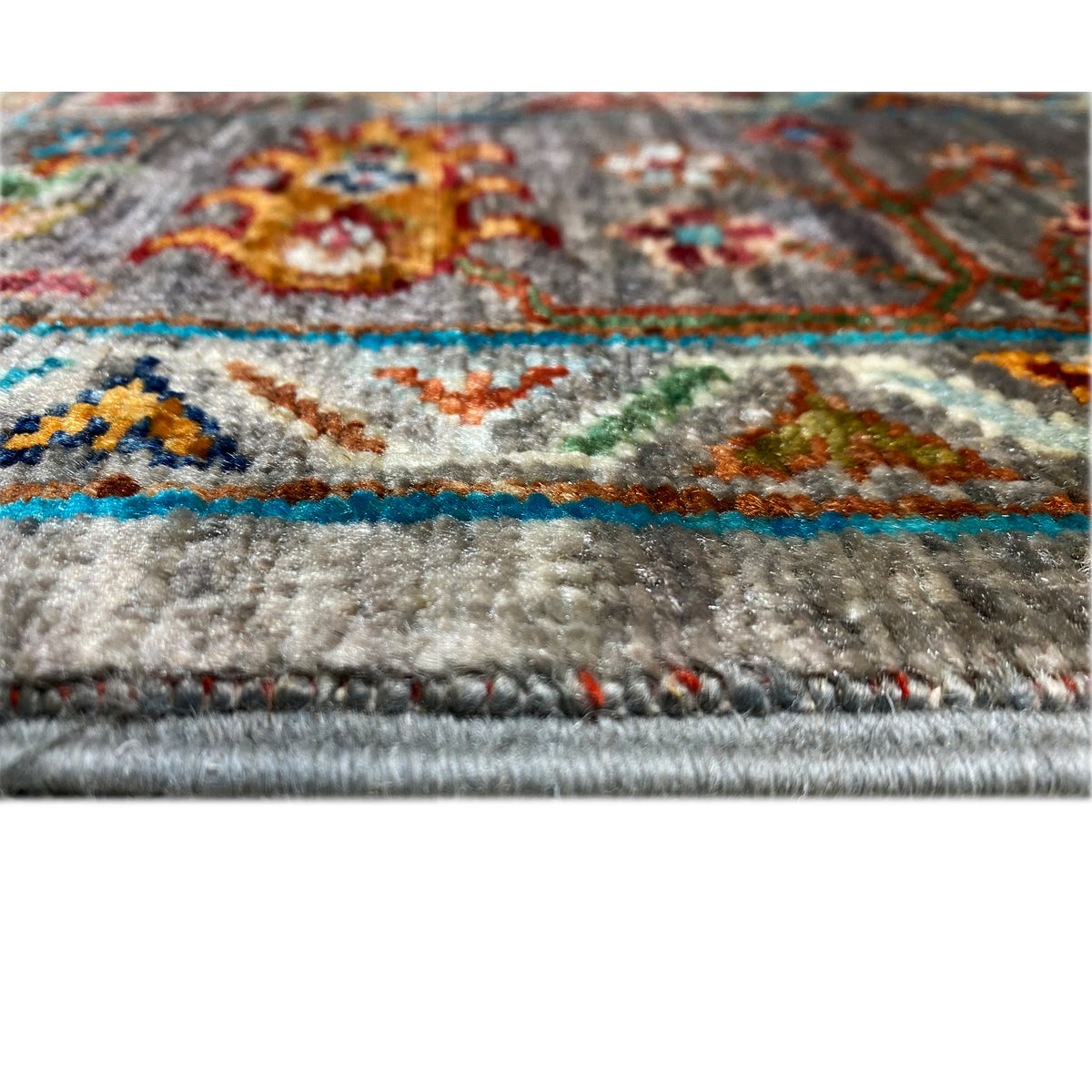 Detail at the edge: gray carpet pile surface with a colored border and short fringes
