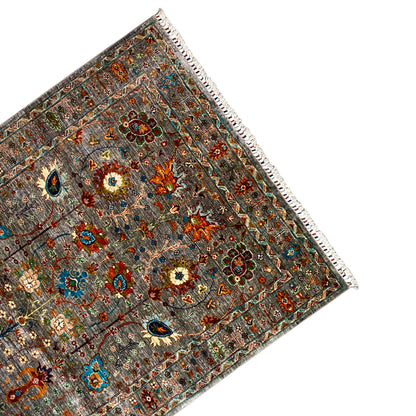 Gray corner Khorjin rug; multicolored decorative motifs, border, and fringe along the hem