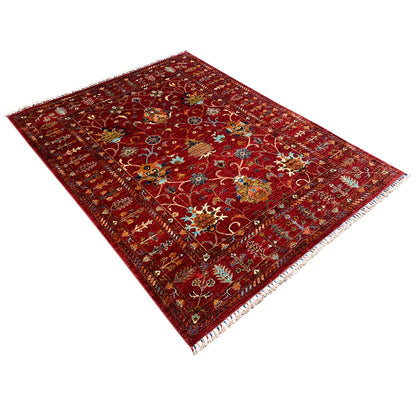 Red Khorjin rug at an angle, detailed ornamental pattern, fringed edges